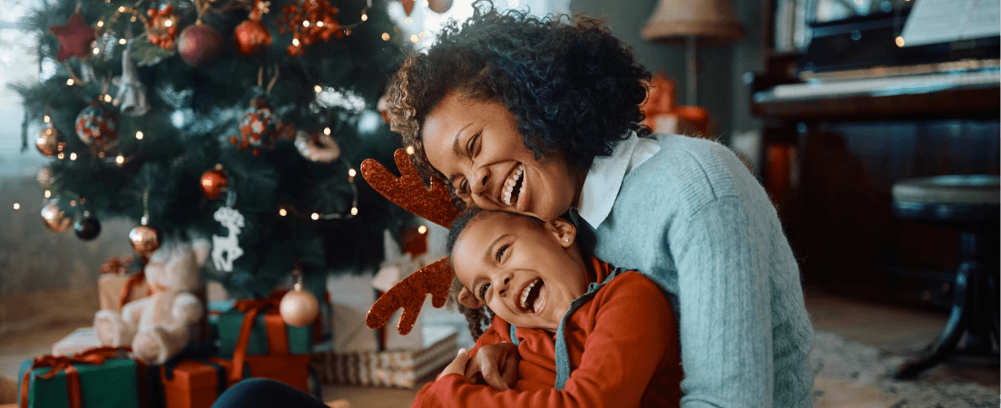 a mother and child in front of Christmas tree