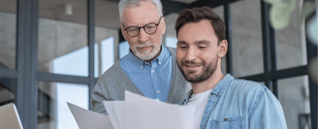 a younger and older man looking at loan paperwork