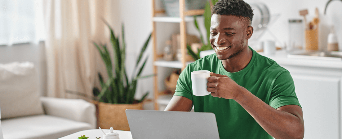 A man drinking coffee and neobanking on his laptop.