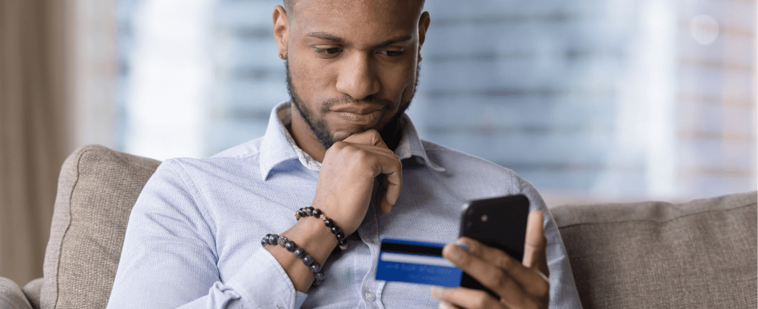 thoughtful man holding credit card and phone