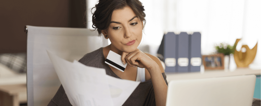 a woman holding her credit card looking at papers