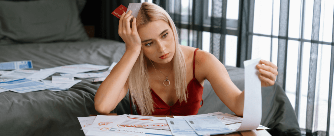 worried woman holding credit cards looking at bills