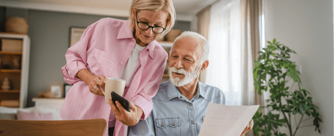 Older woman shows man holding papers her phone