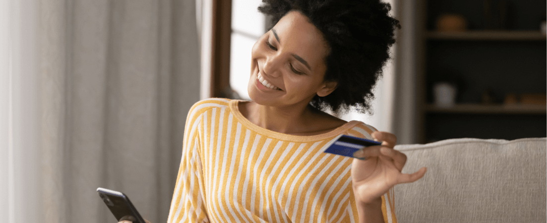 smiling woman holding her credit card and phone