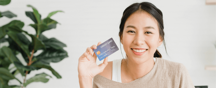 woman holds credit card by face