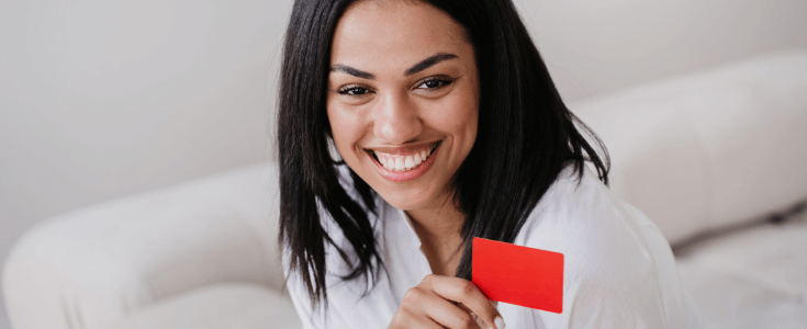 smiling woman holds a red credit card