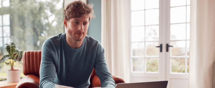 man sitting on couch at his laptop