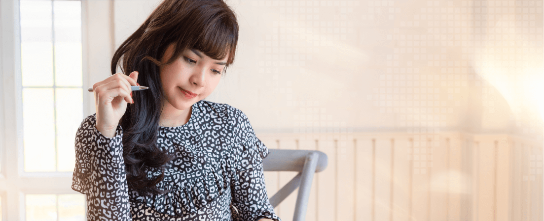 young woman holds pen while thinking