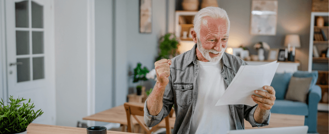 Older man happily reads papers in living room