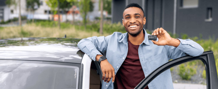 Man holding car keys standing in front of his car