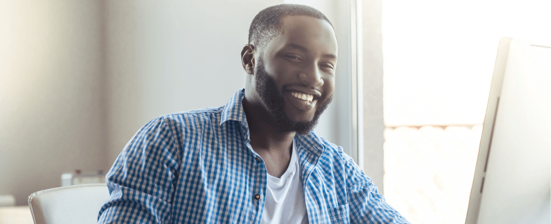 man smiles as he sits at his computer