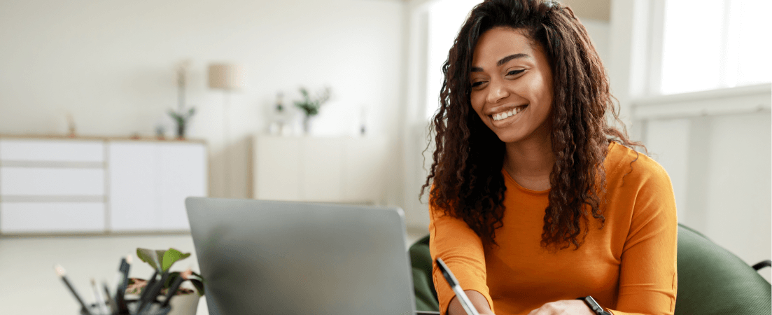 Smiling woman at her laptop taking notes